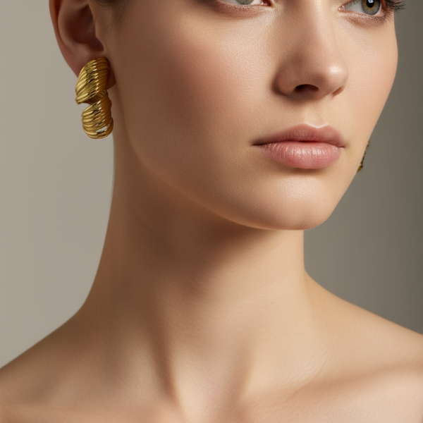 Close-up of a woman wearing golden stud earrings against a neutral background
