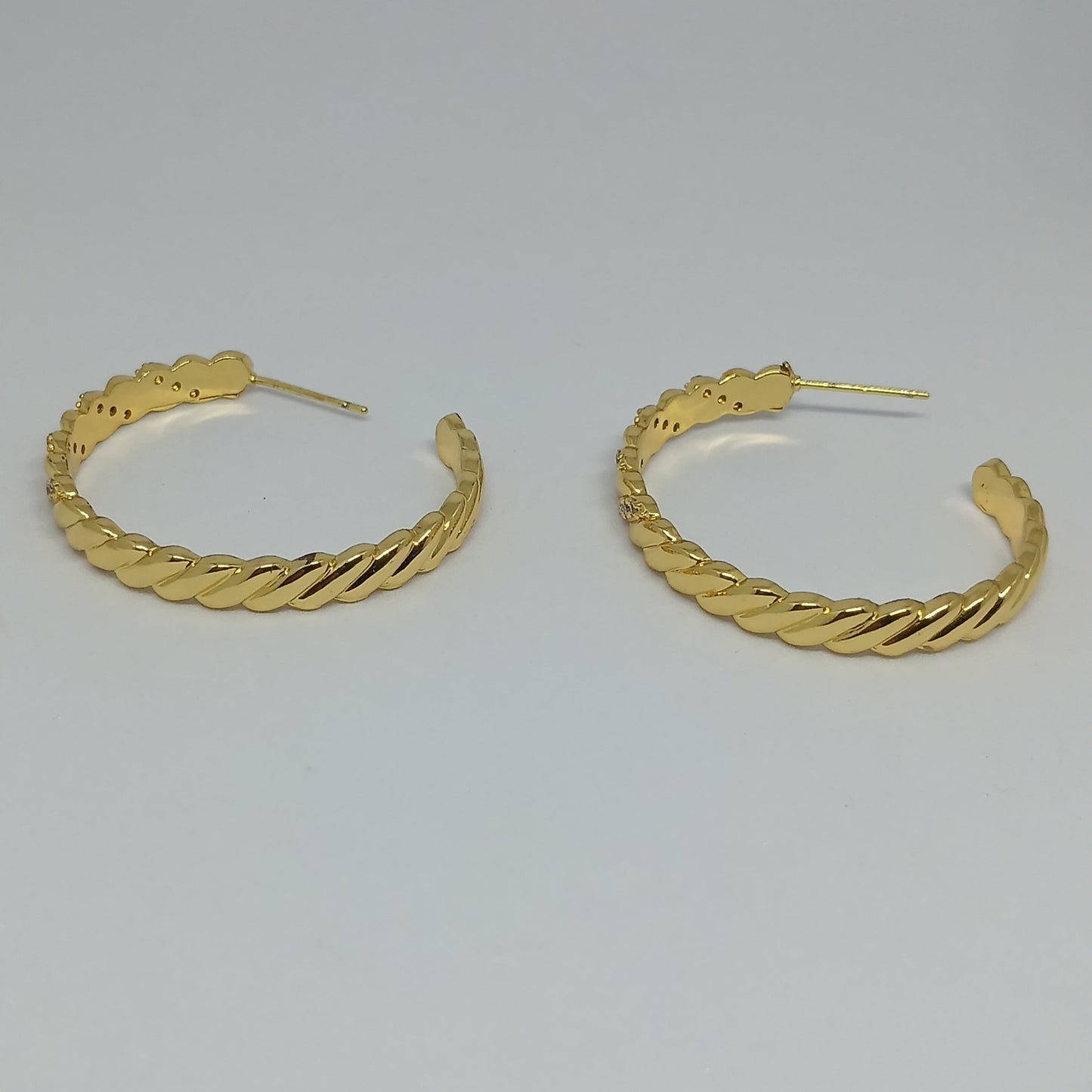 Pair of gold hoop earrings on a light gray background