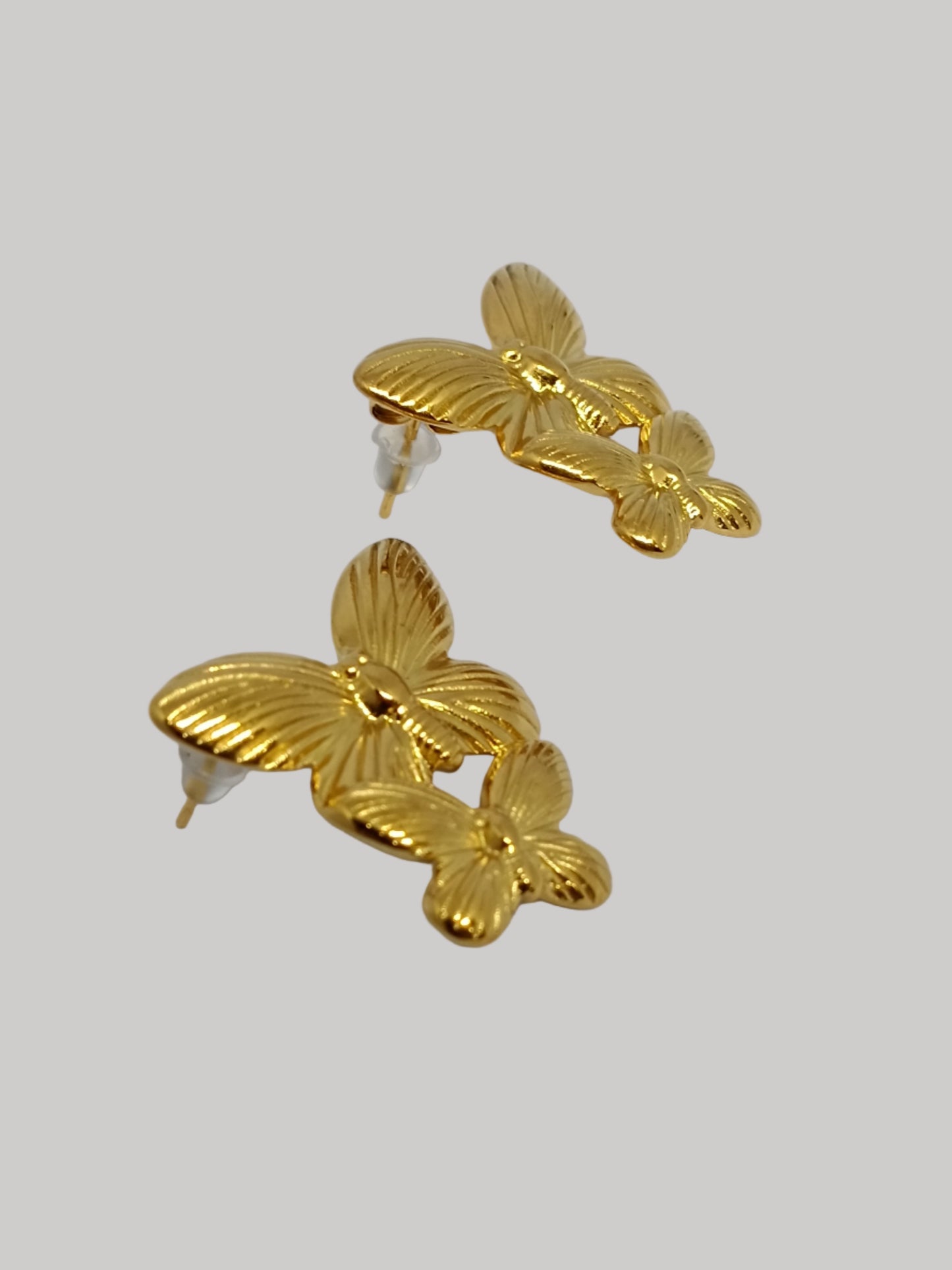 Pair of gold butterfly earrings on a light gray background
