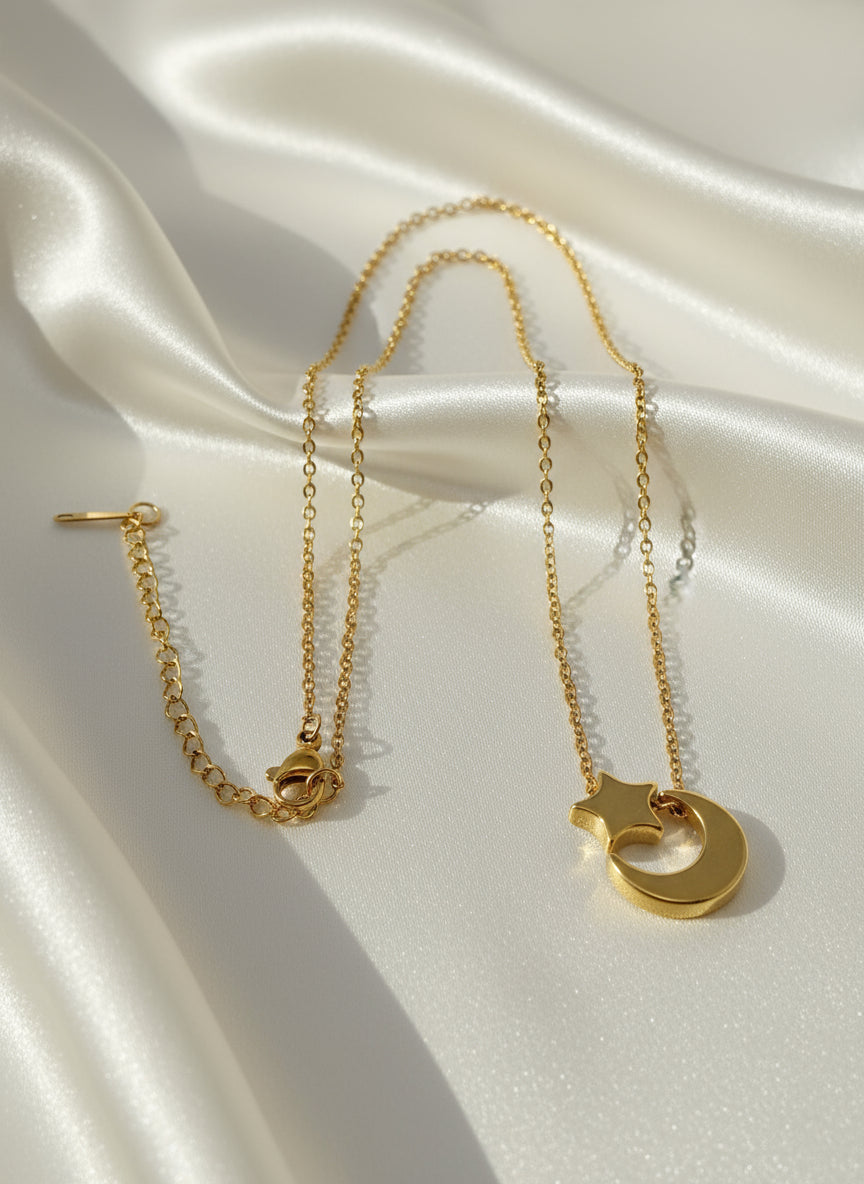 Gold necklace with a moon and star pendant on a light gray background