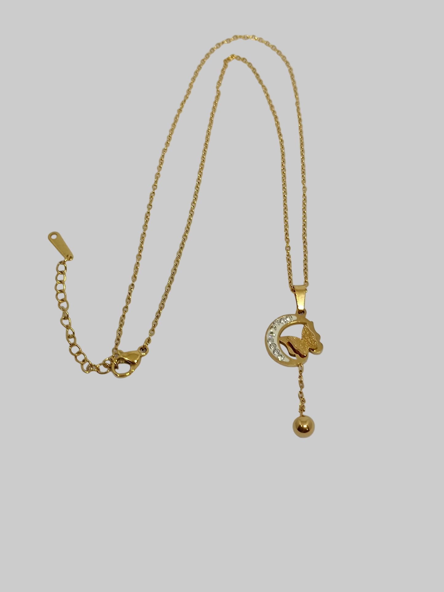 Gold necklace with a small pendant on a light gray background