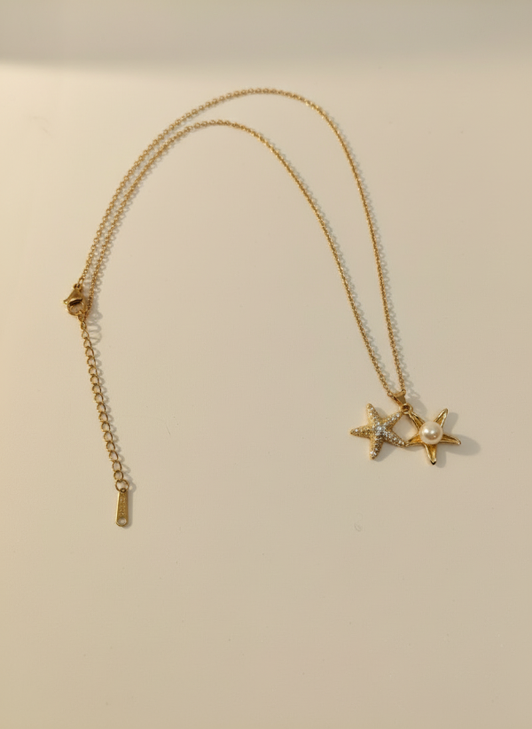 Gold necklace with star-shaped pendants on a beige background
