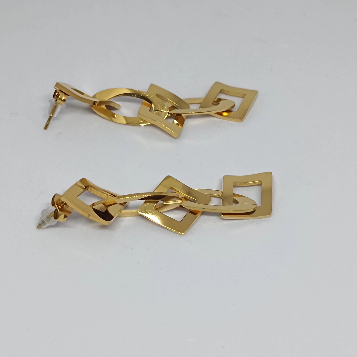 Gold earrings on a light gray background