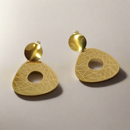 Pair of golden earrings on a light gray background