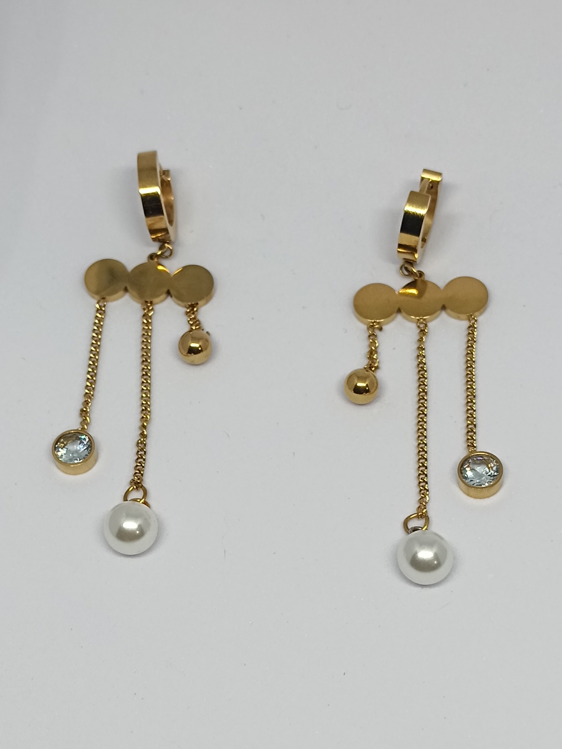 Gold earrings with pearl drops on a light gray background