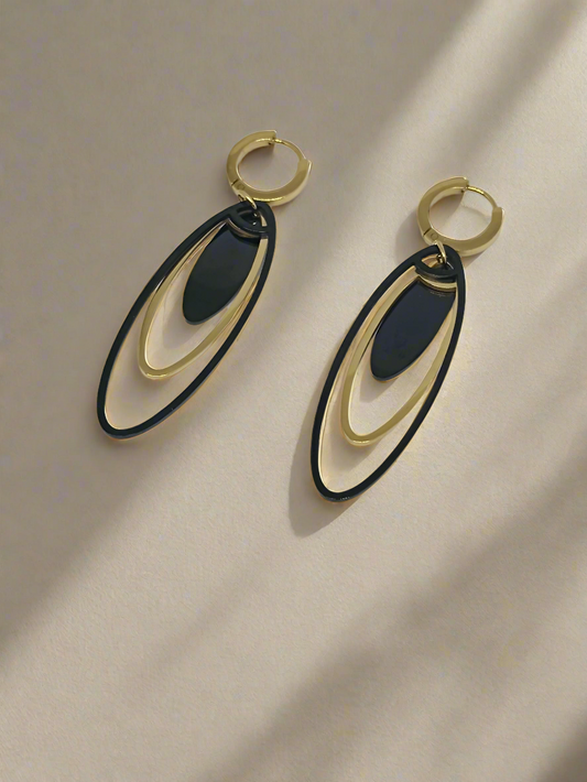Pair of gold and black earrings on a light gray background