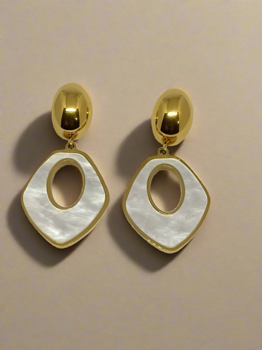 Gold and white earrings on a beige background