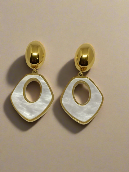 Gold and white earrings on a beige background