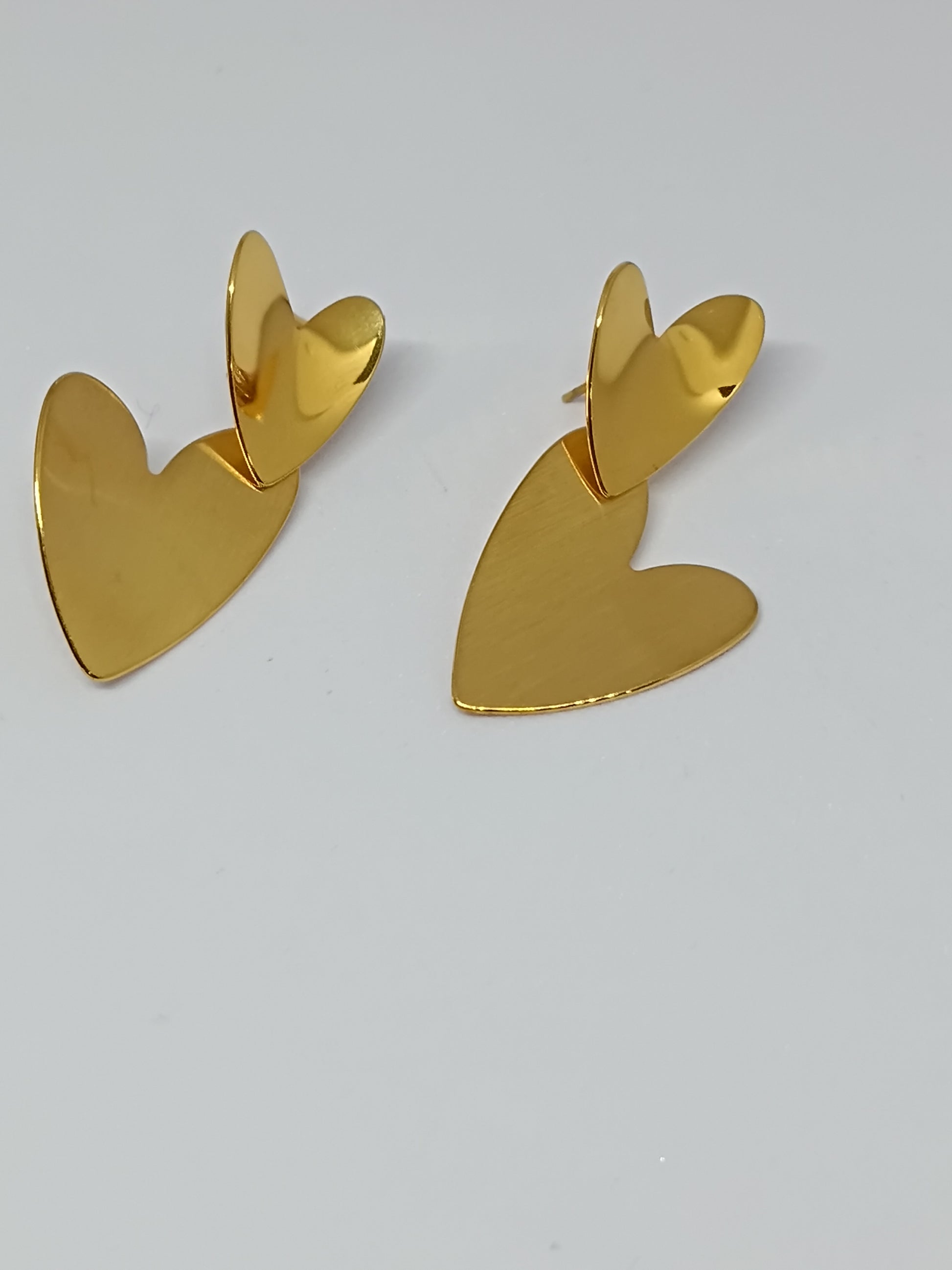 Gold heart-shaped earrings on a light gray background