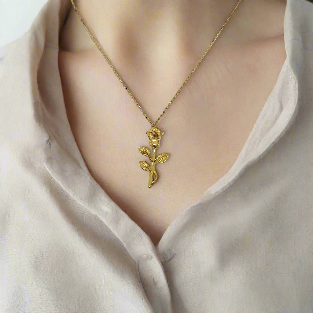 Gold rose-shaped pendant on a chain against a white background
