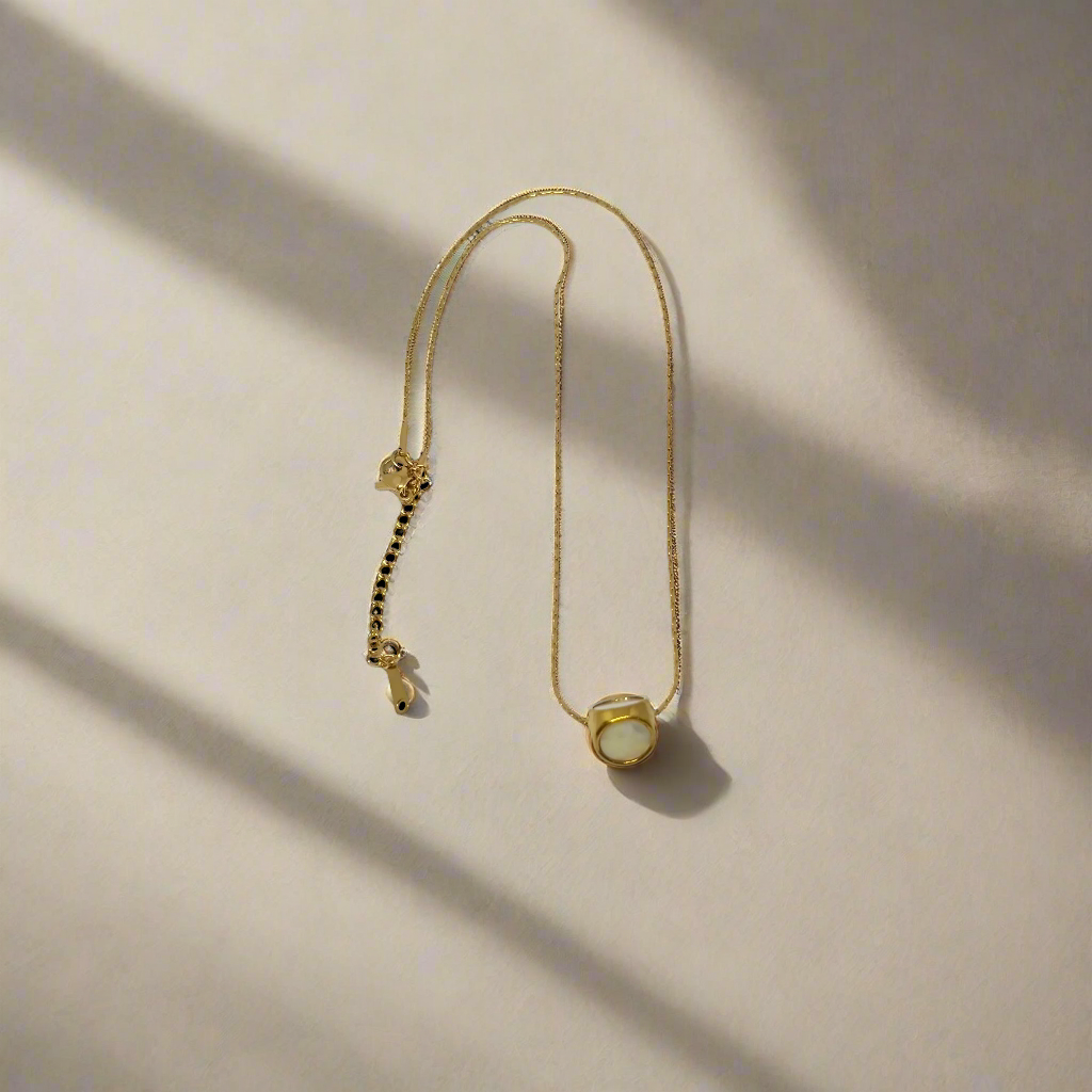 Gold necklace with a small pendant on a white background