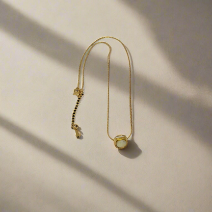 Gold necklace with a small pendant on a white background