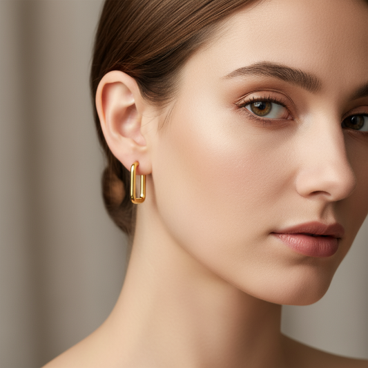 Close-up of a woman wearing a golden earring against a neutral background