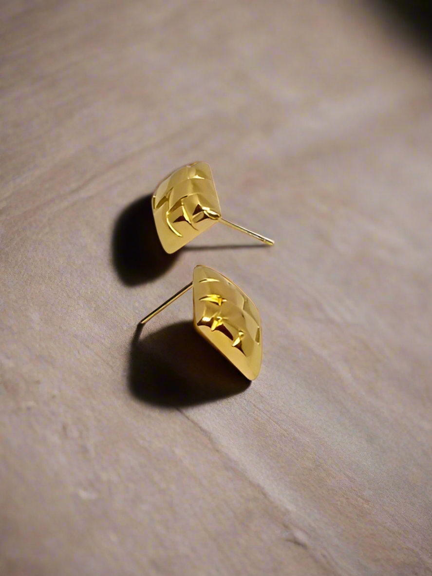 Gold earrings on a pink background