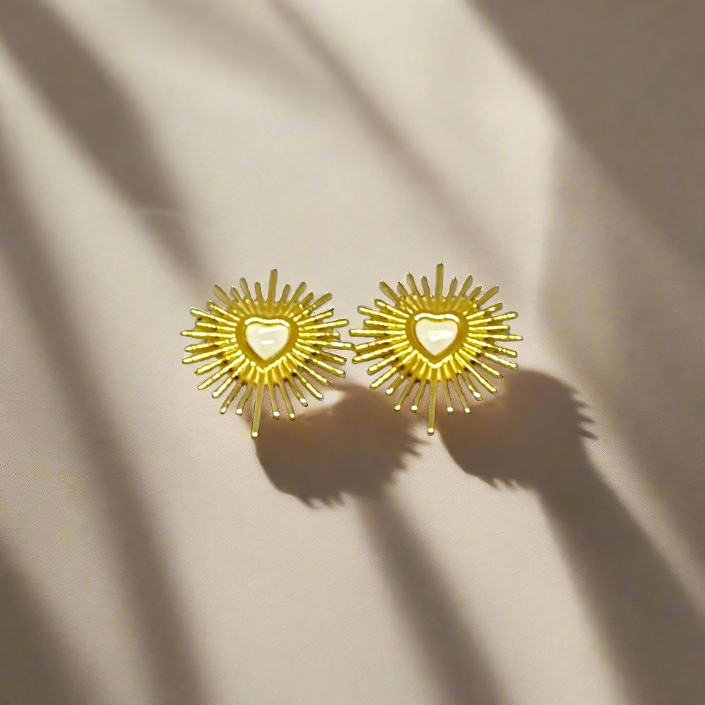 Gold sunburst earrings with heart centers on a white background