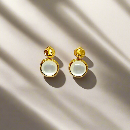 Gold earrings with round white stones on a white background