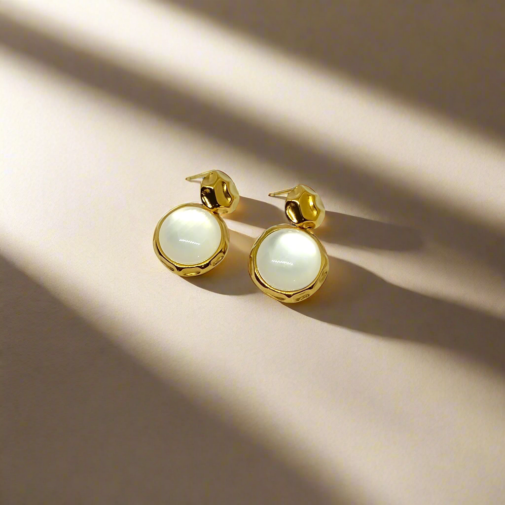 Gold earrings with white round stones on a white background
