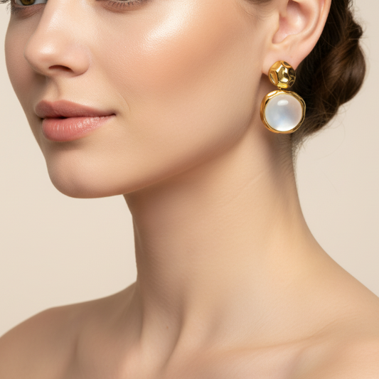 Close-up of a woman wearing golden earrings with a beige background