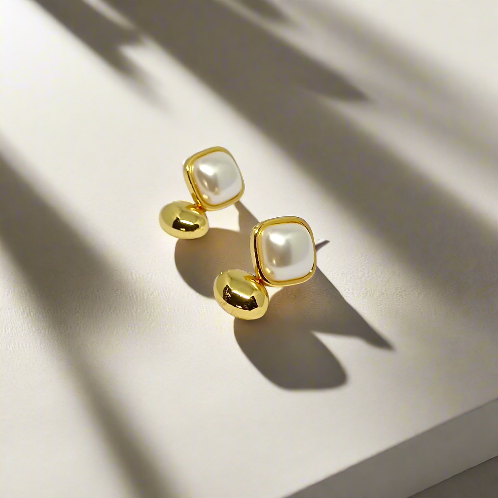 Pair of gold earrings with pearl-like stones on a white background
