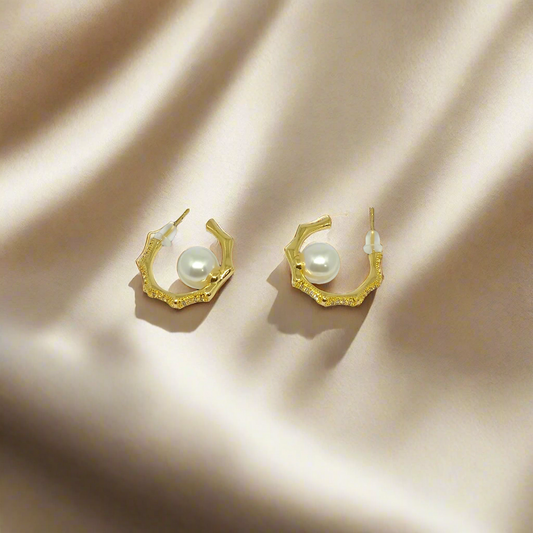 Gold hoop earrings with pearls on a white background