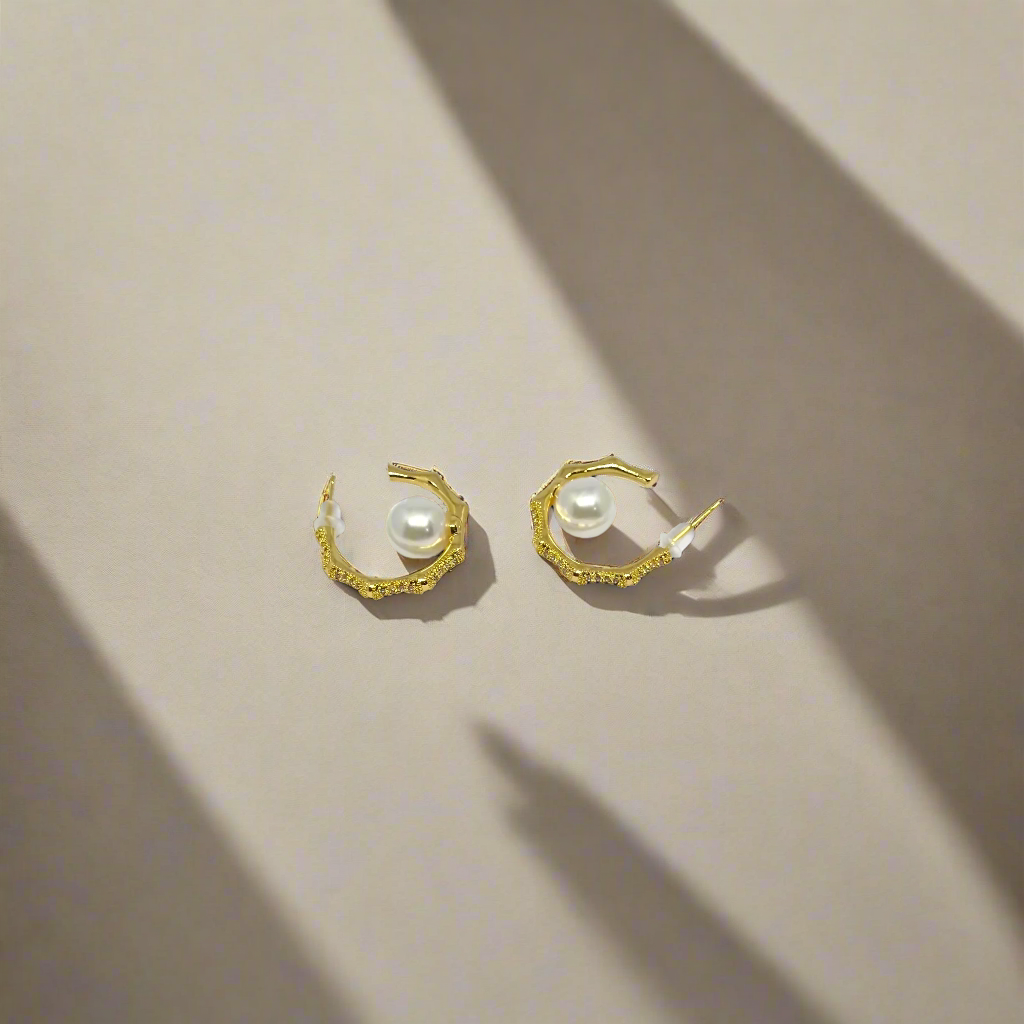 Pair of gold hoop earrings with pearls on a white background