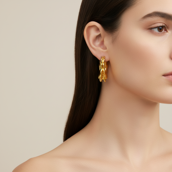 Golden earring worn by a model on a beige background
