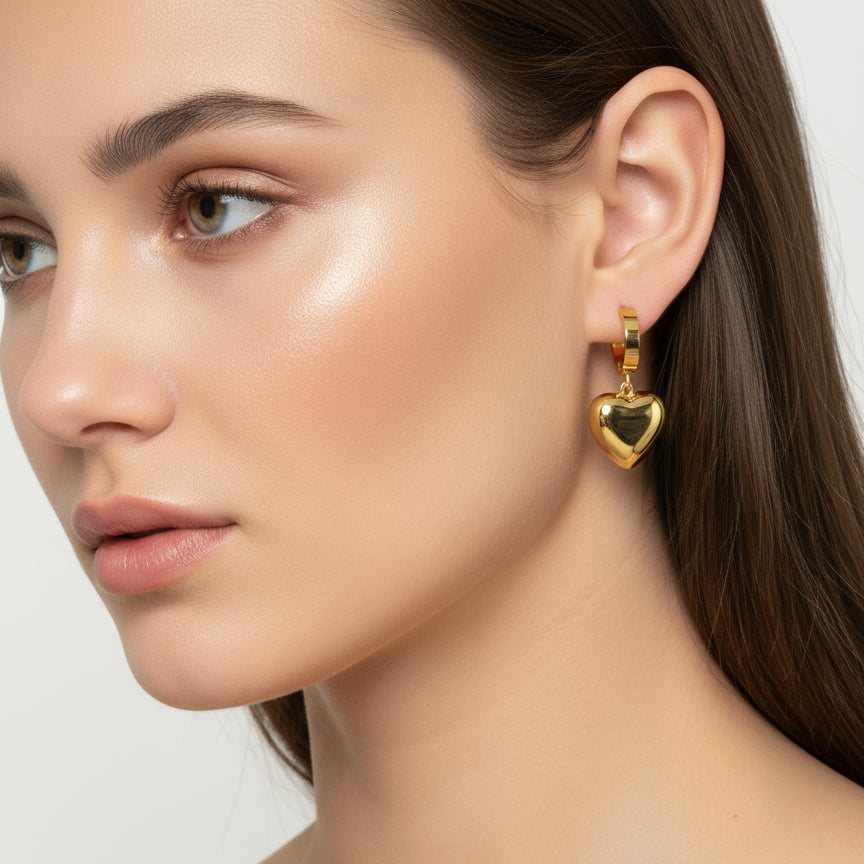 Close-up of a woman wearing golden heart-shaped earrings on a neutral background