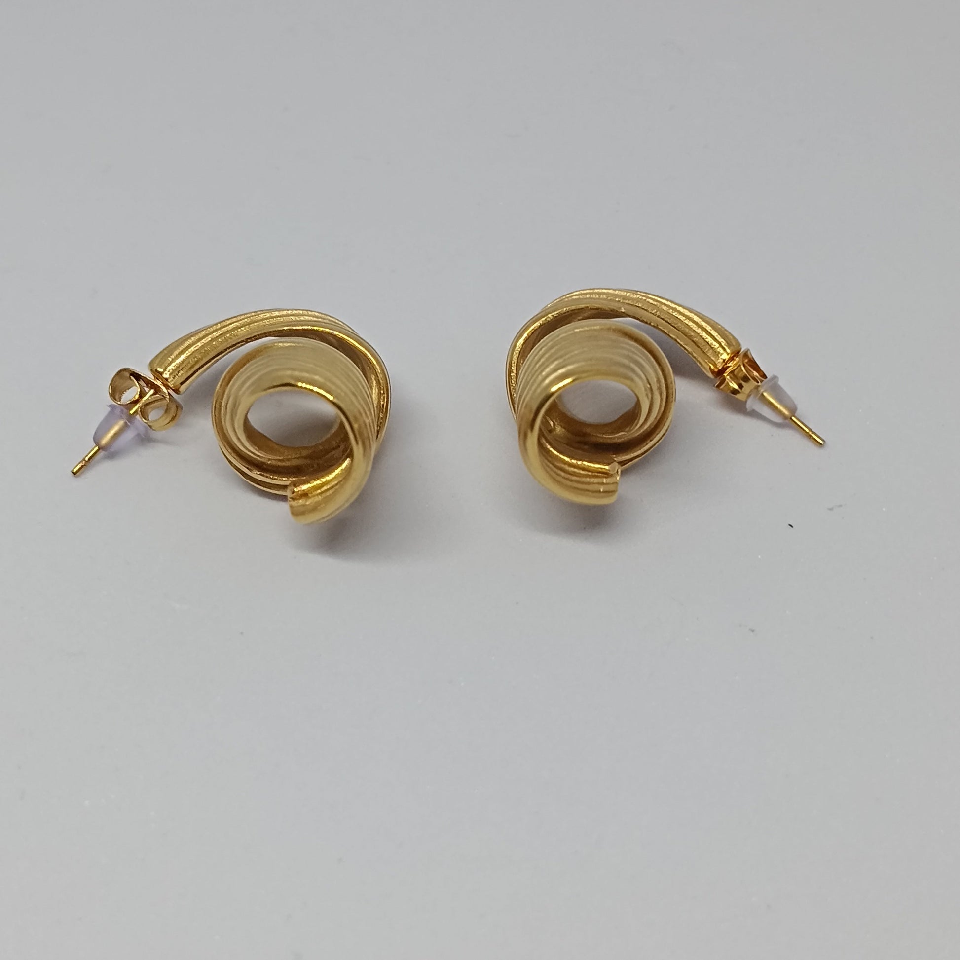 Pair of gold spiral earrings on a light gray background