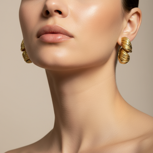 Close-up of a woman wearing golden earrings with a neutral background