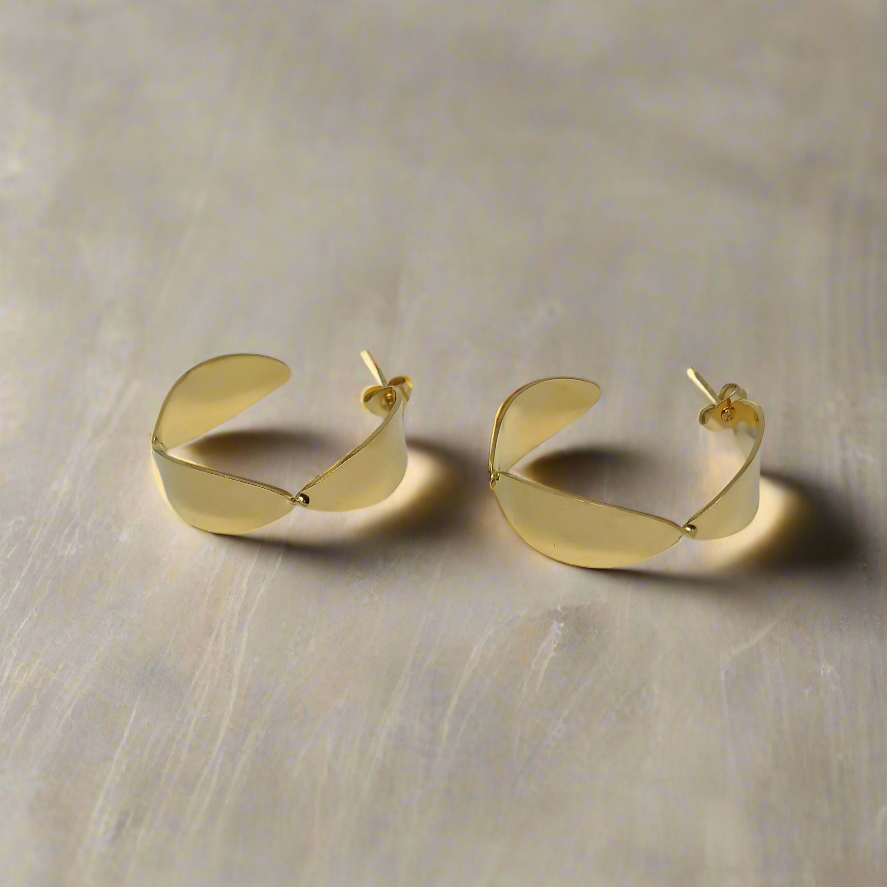 Golden half hoop earrings on a beige background
