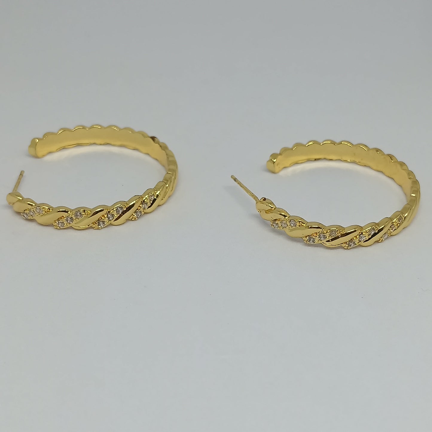 Pair of gold hoop earrings on a light gray background