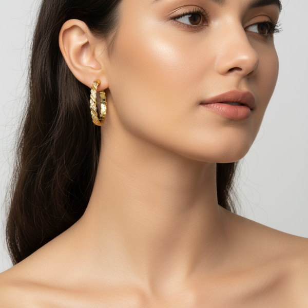 Close-up of a woman wearing golden hoop earrings with a neutral background