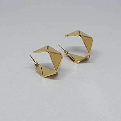 Gold geometric hoop earrings on a light gray background