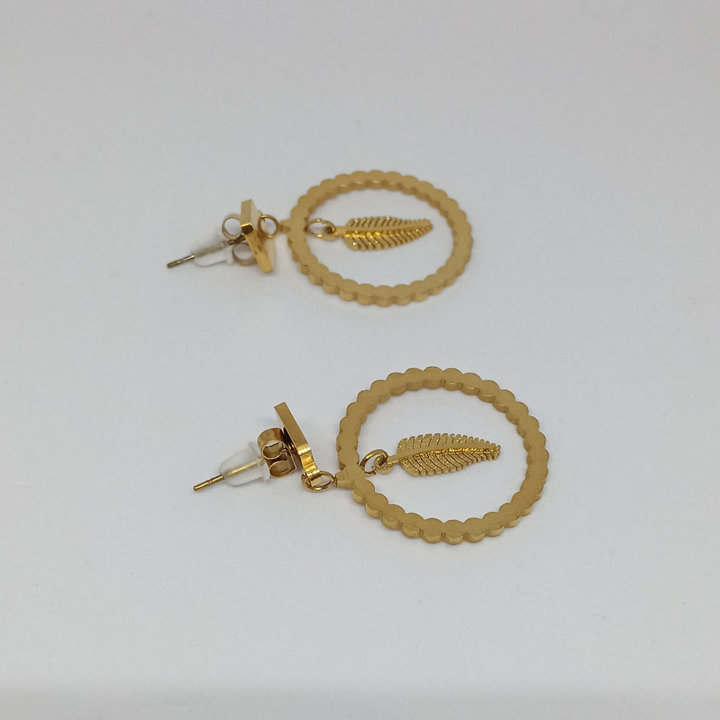 Pair of golden earrings on a light gray background
