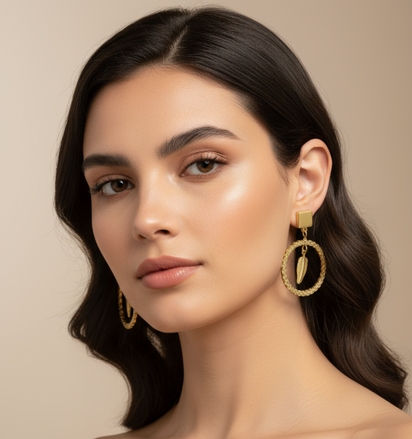 Woman wearing golden stud earrings against a neutral background