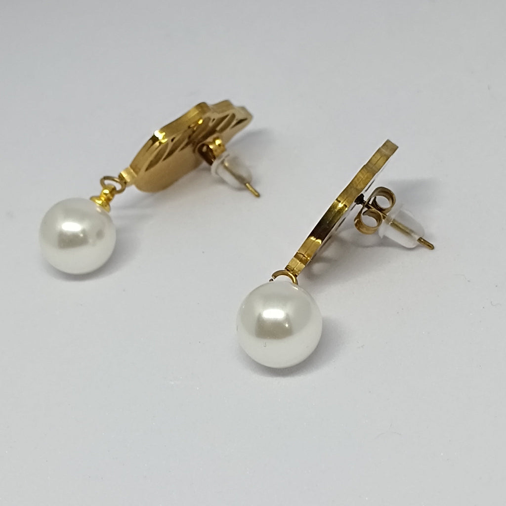 Gold earrings with pearl drops on a light gray background