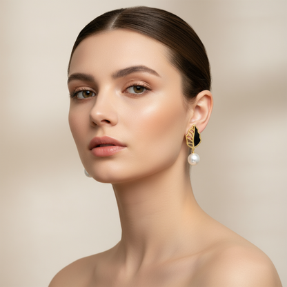 Woman wearing golden earrings with pearls against a beige background
