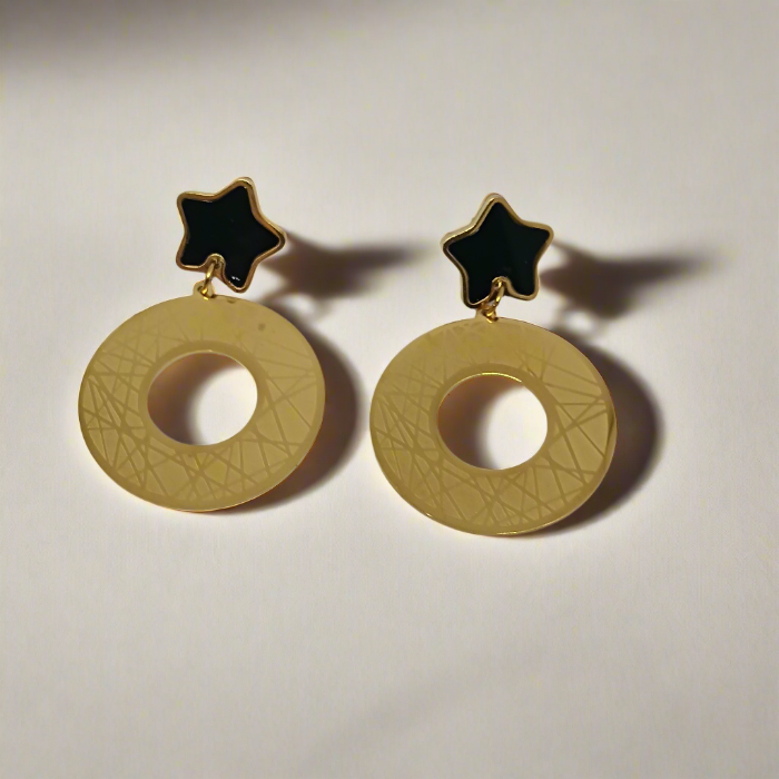 Gold earrings with black star tops on a white background