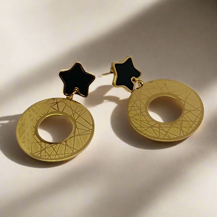 Gold earrings with star-shaped tops on a light background