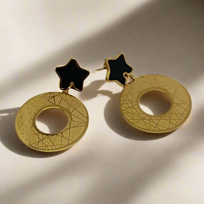 Gold earrings with star-shaped tops on a light background