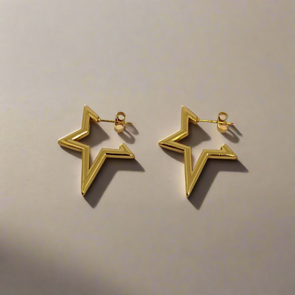 Gold star-shaped earrings on a beige background
