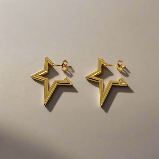 Gold star-shaped earrings on a beige background