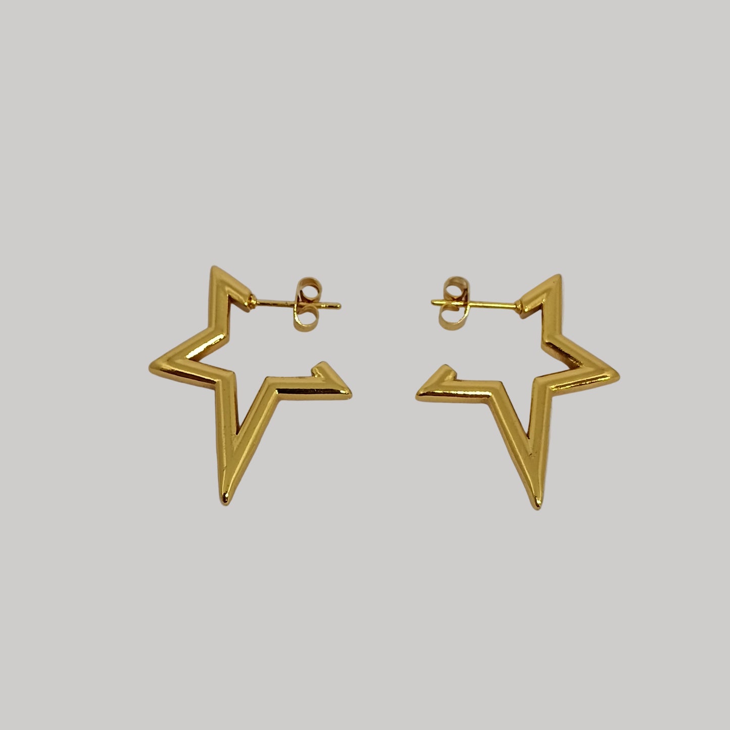 Gold star-shaped earrings on a light gray background