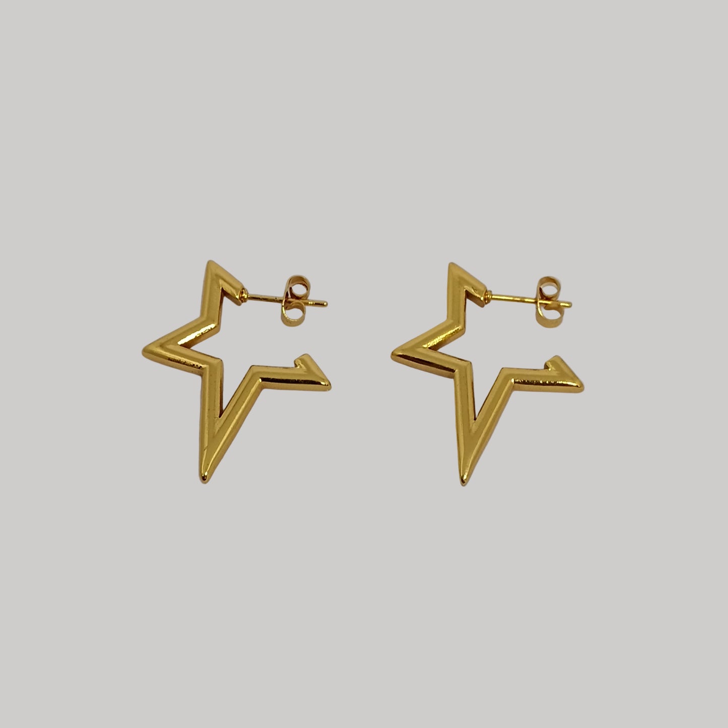 Gold star-shaped earrings on a light gray background