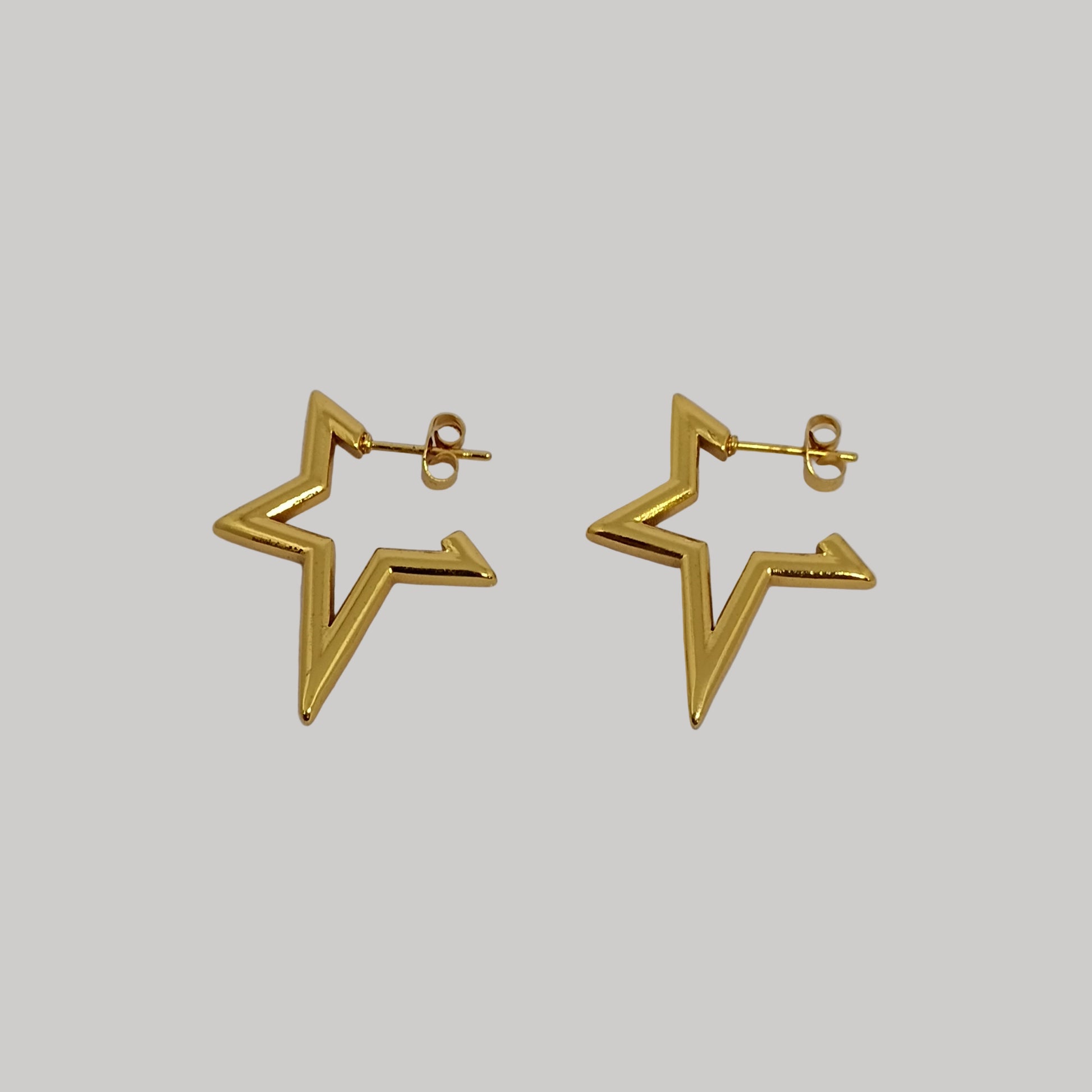 Gold star-shaped earrings on a light gray background