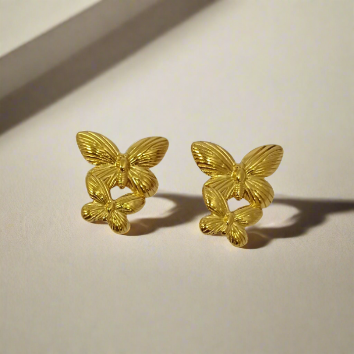 Pair of gold butterfly earrings on a light gray background