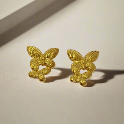 Pair of gold butterfly earrings on a light gray background