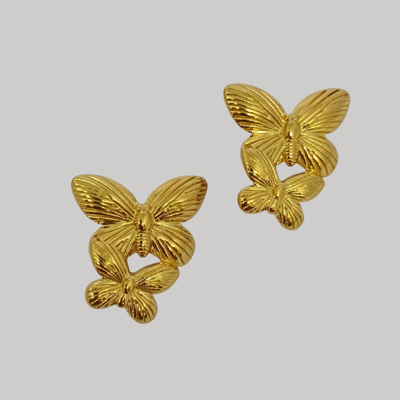 Pair of gold butterfly earrings on a light gray background
