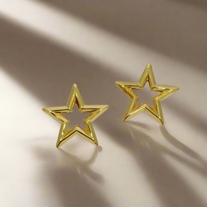 Gold star-shaped earrings on a light gray background