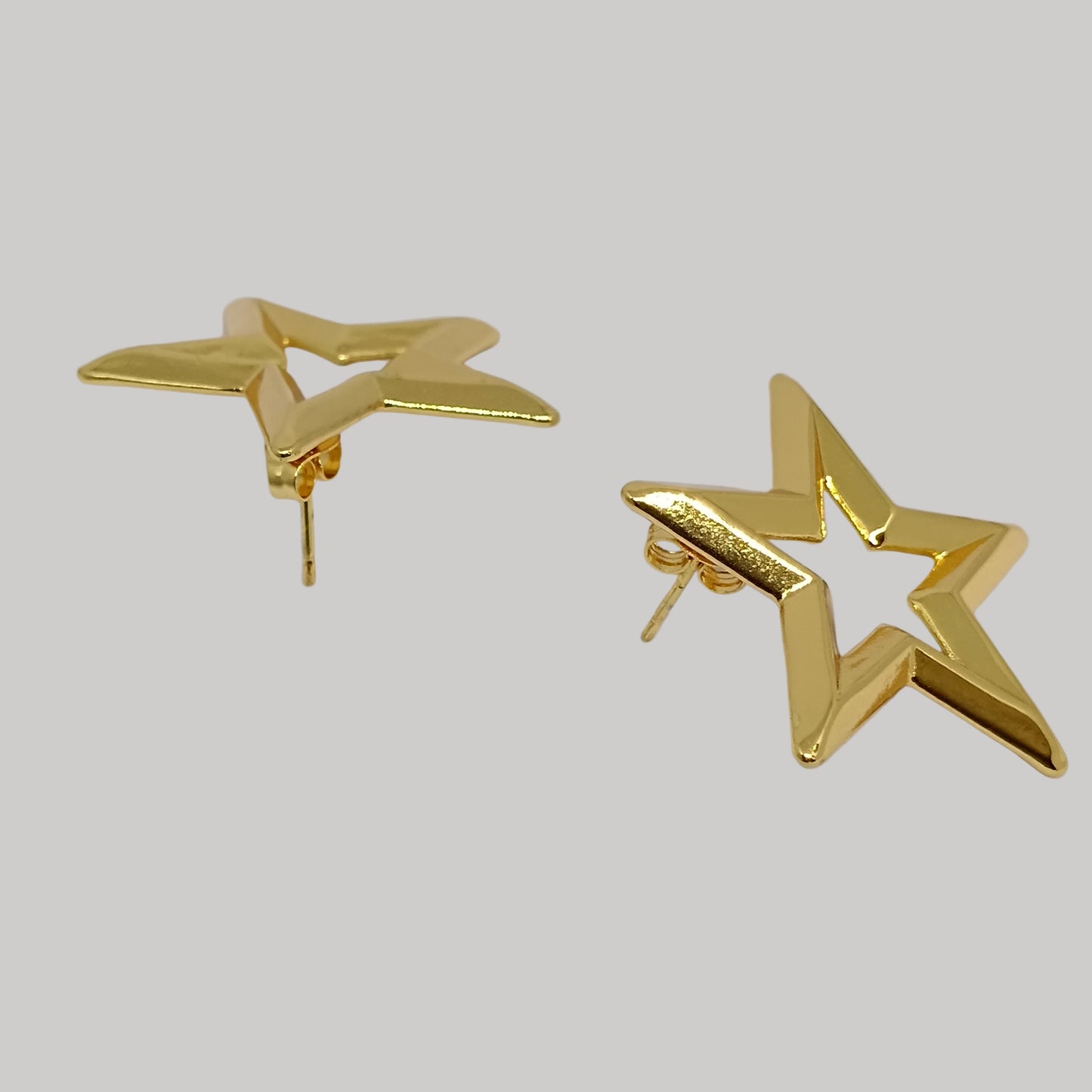 Gold star-shaped earrings on a light gray background